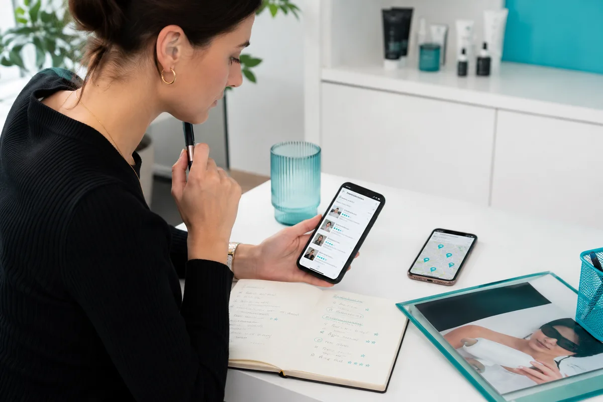 Lecture de commentaires sur un téléphone et prise de notes. Les avis affichés sont illustratifs.
